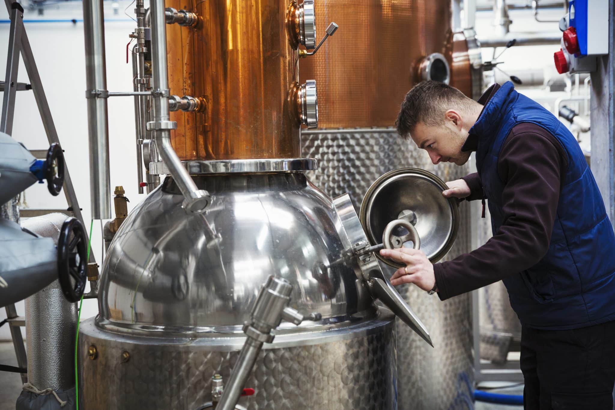 Man looking into a metal tank in a distillery. Man looking into a metal tank in a distillery.