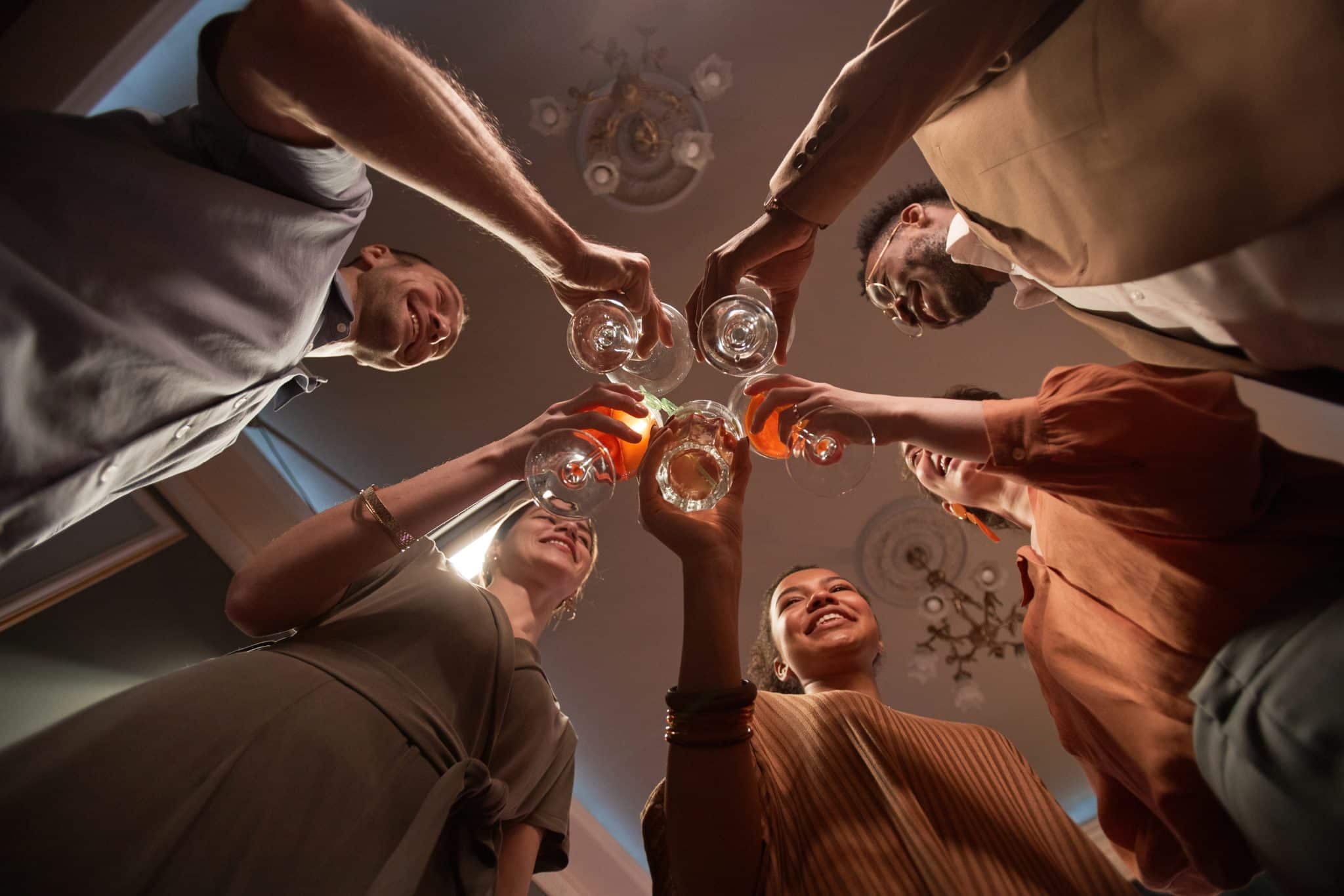 Low angle view at multi-ethnic group of people clinking glasses while enjoying party indoors