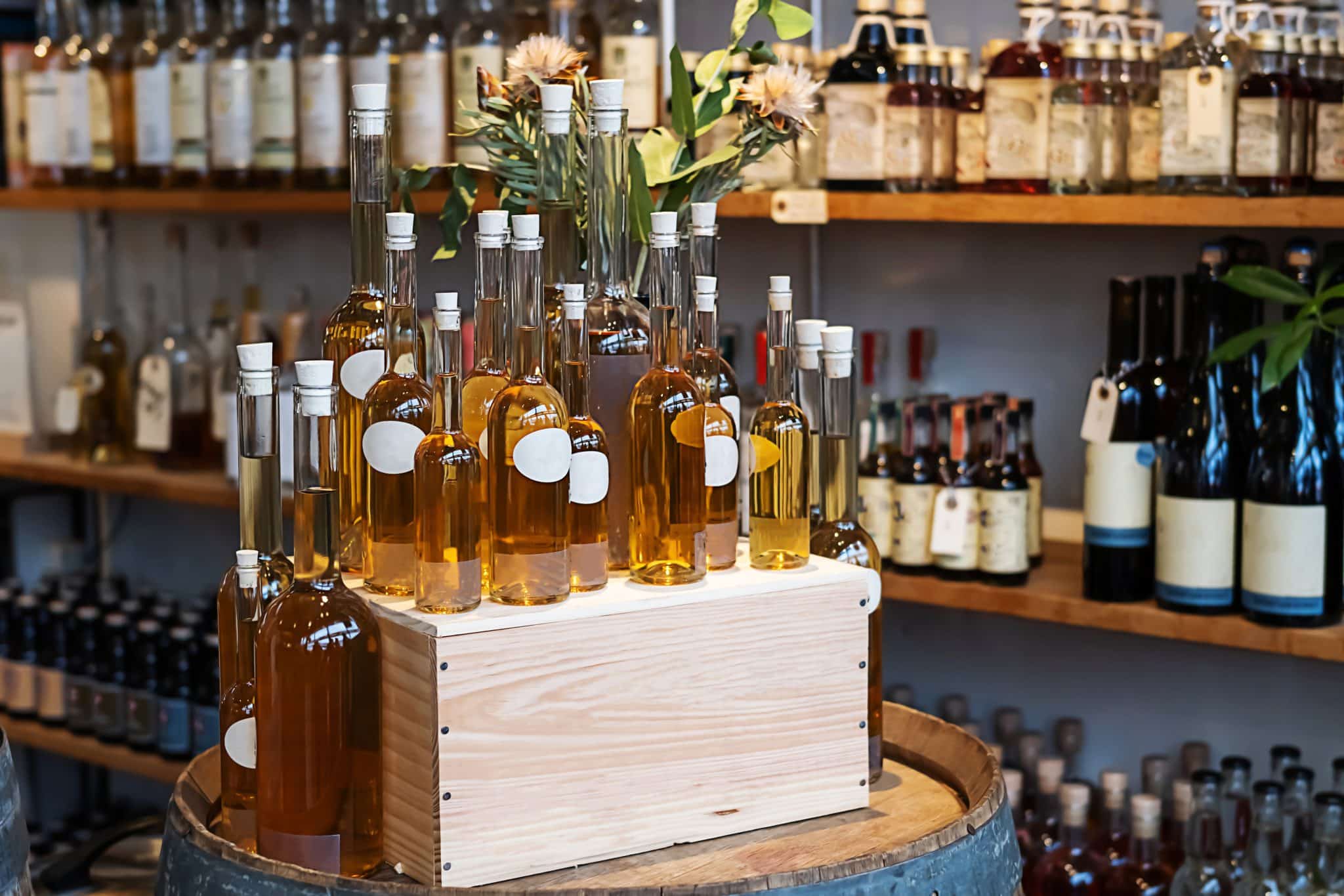 Bottles with cognac, shelves with alcoholic drinks in the shop. Bottles with cognac on a wooden box, shelves with alcoholic drinks in the shop.